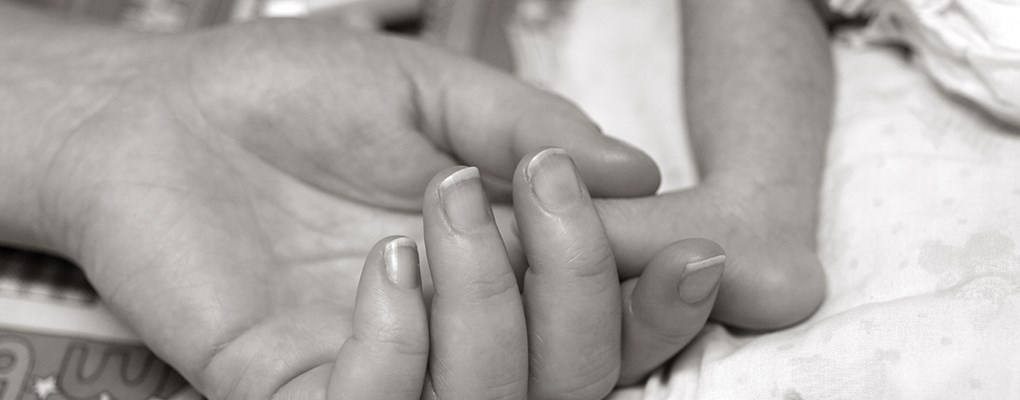 Mother's hand touching premature baby's foot